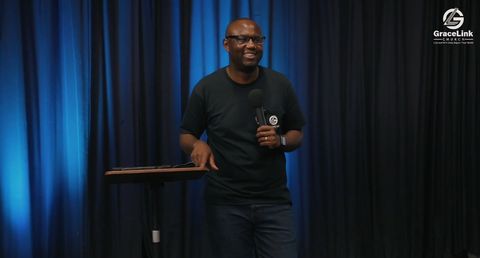 Pastor Daniel Manyanga preaching on stage at GraceLink Church